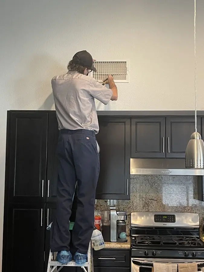 Technician inspecting an air vent during HVAC service in North Arlington